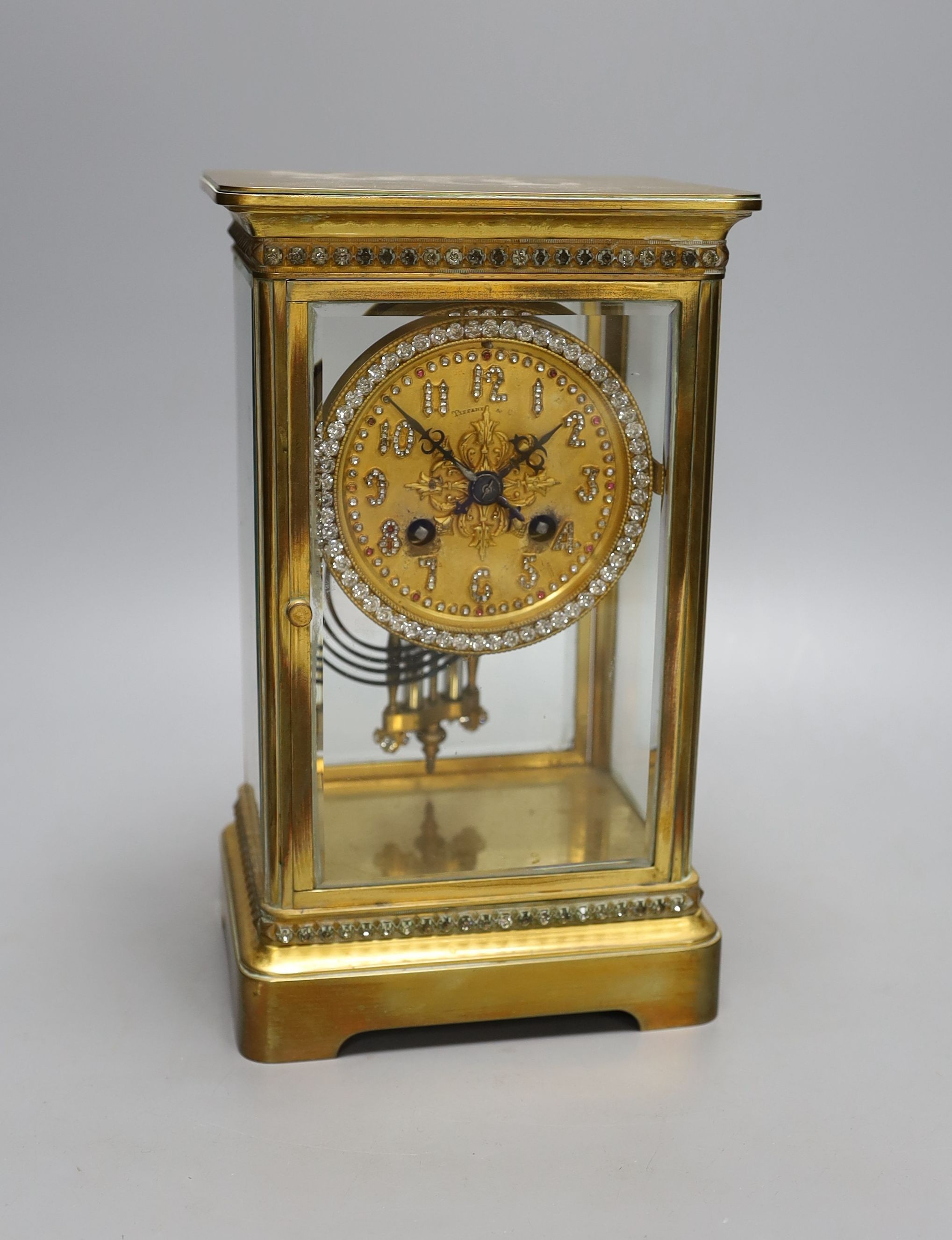 An early 20th century paste set brass four glass mantel clock retailed by Tiffany & Co. Includes paste set mercury pendulum. No key. Height - 26cm